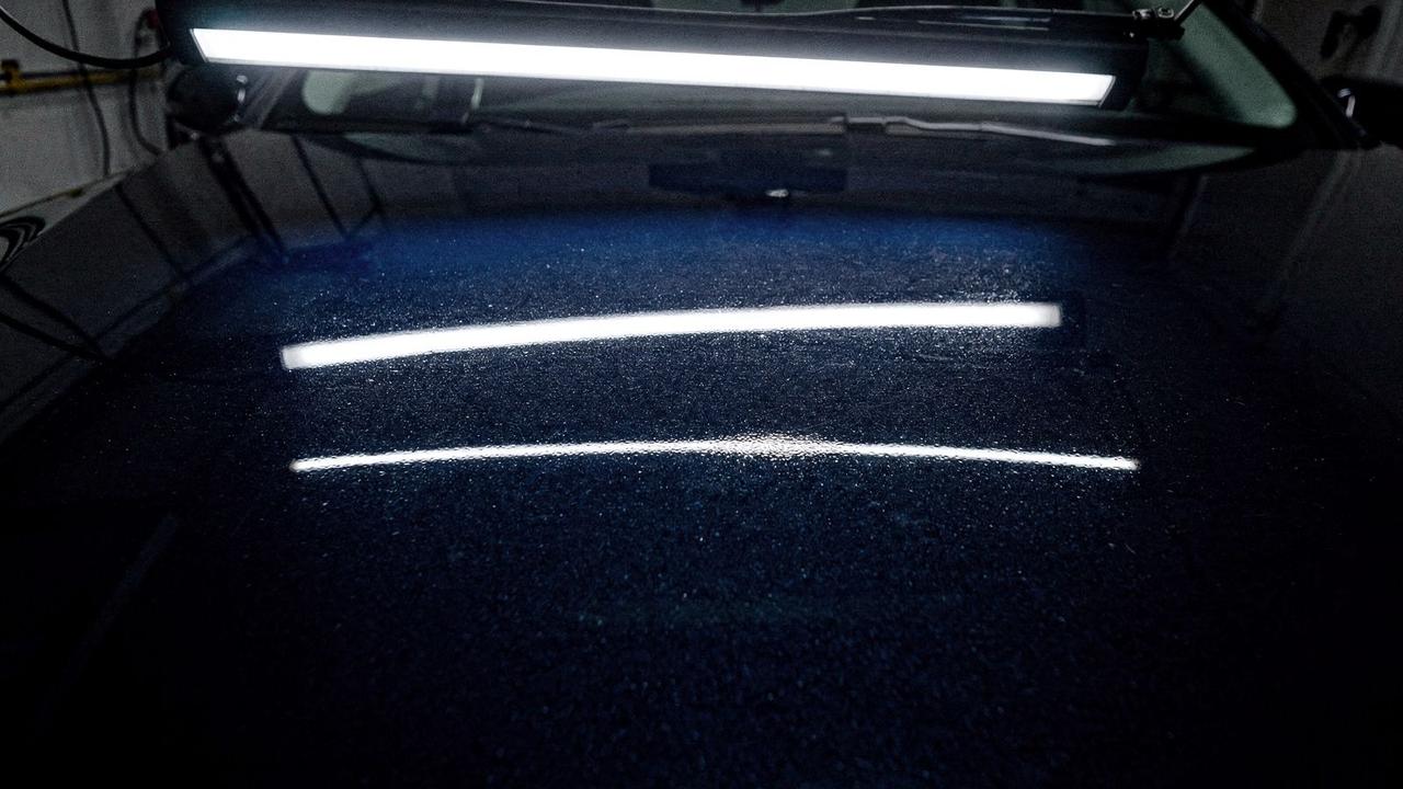 Dark navy bonnet after correction and coating under a single studio LED bar